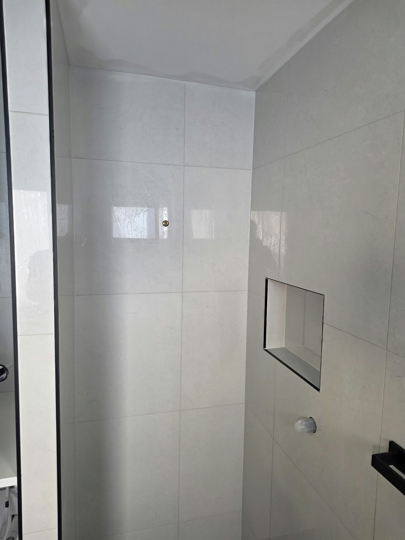 New shower with floor-to-ceiling tiling and a built-in recessed niche