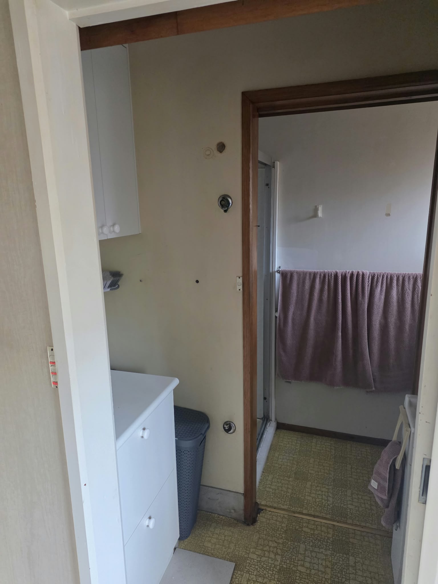 Laundry before renovation, with dated cabinetry and worn vinyl flooring