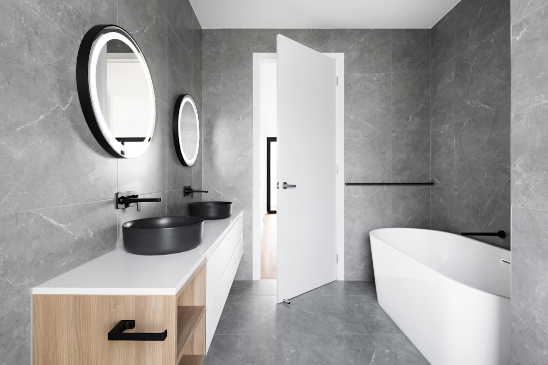 Finished bathroom by a Melbourne bathroom renovation company, with grey tiles, double vanity and freestanding bath