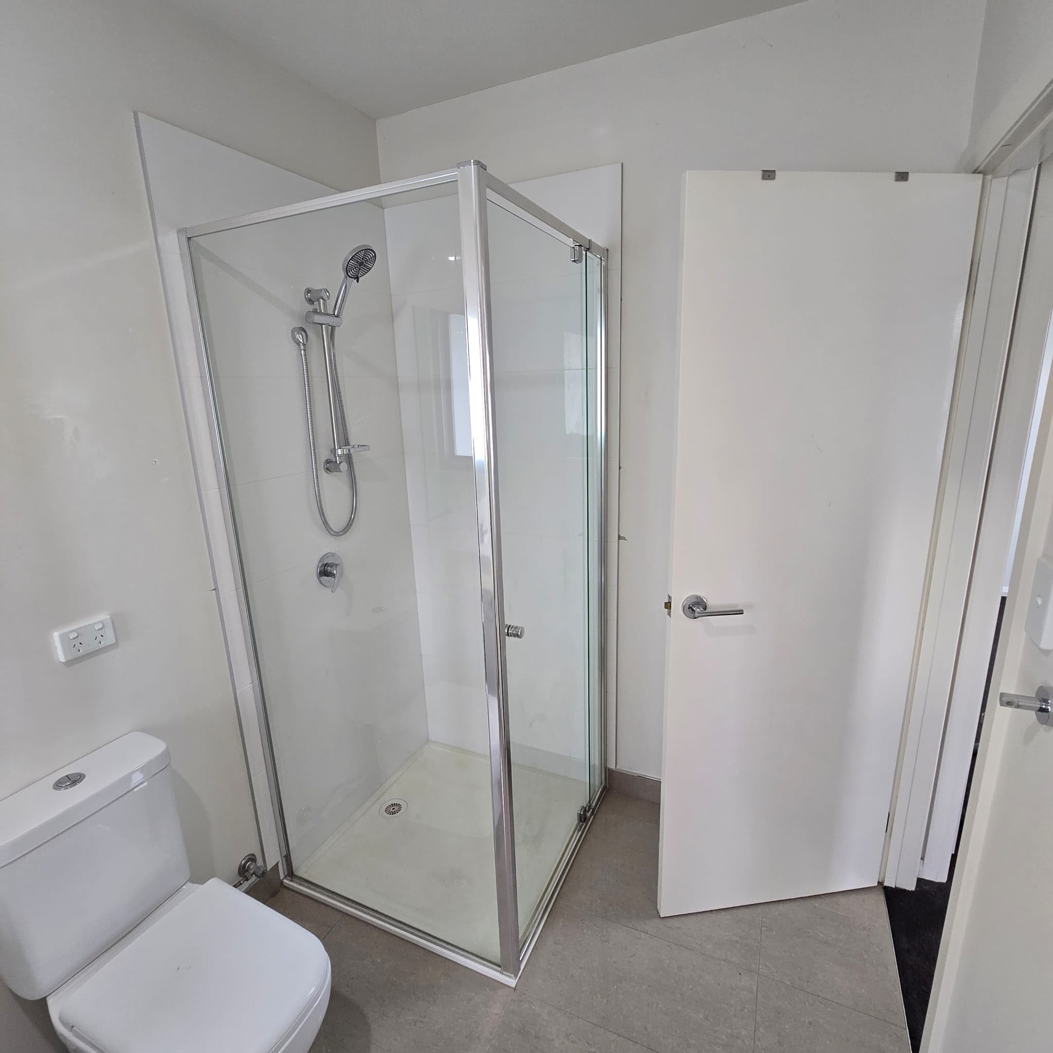 Finished shower with white tiling, a framed glass screen and chrome fittings