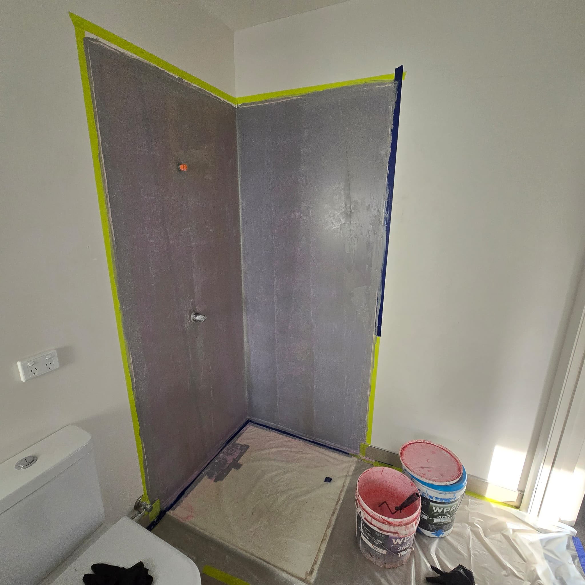 Waterproofing membrane applied to the shower walls and floor, taped at the edges